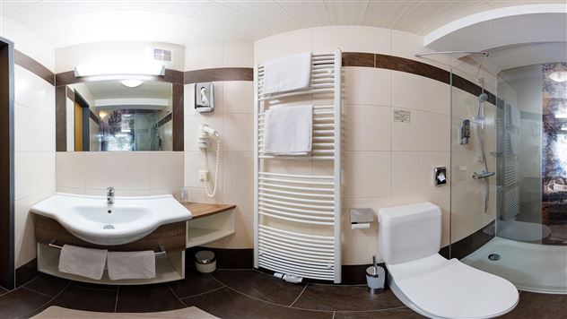 A modern bathroom with a shower and a sink. There are towels and a clean, bright decor.