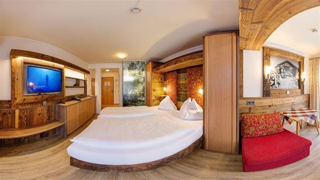 A cozy hotel room with two beds, wooden paneling, and a television. The decor is modern and inviting, featuring a small seating area.