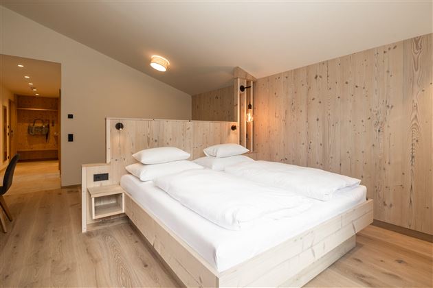 Ein modernes Schlafzimmer mit einem Doppelbett und Holzverkleidung. Die Atmosphäre ist hell und einladend.
