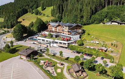 Ein modernes Hotel in einer malerischen Berglandschaft. Umgeben von grünen Wäldern und einem ruhigen Parkplatz.