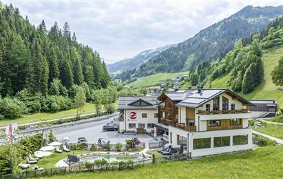 Ein gemütliches Gebäude in einer malerischen Landschaft mit Bergen und grünen Wäldern. Die Umgebung ist einladend und zeigt einen ruhigen Ort zur Erholung.