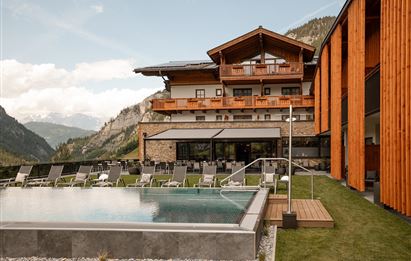 Ein modernes Hotel mit Holzfassade und einem Poolbereich. Die Aussicht auf die Berge ist atemberaubend und die Umgebung ist entspannend.