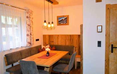 Ein gemütlicher Essbereich mit einem Holztisch und bequemen Sitzen. Die warmen Farben und die dekorativen Lampen verleihen dem Raum eine einladende Atmosphäre.