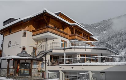 Ein charmantes Hotel im Berggebiet, umgeben von schneebedeckten Hügeln. Die Architektur kombiniert traditionelles Holzdesign mit modernen Elementen.