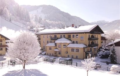 A beautiful, snowy winter landscape with a yellow building. The trees are covered with snow and the mountains are visible in the background.