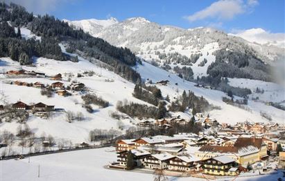 Eine malerische Winterlandschaft mit schneebedeckten Bergen und einem charmanten Dorf im Tal. Die Szene ist geprägt von einer ruhigen, weißen Atmosphäre.