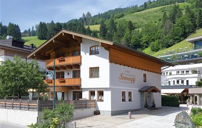 Ein charmantes alpine Haus mit Holzverkleidung und Balkonen. Umgeben von grünen Bergen und einer ruhigen Atmosphäre.