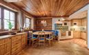 Eine gemütliche Küche im rustikalen Stil mit Holzverarbeitung. Am Tisch stehen Stühle und es gibt Fenster mit schönem Blick.