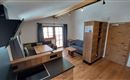 Eine moderne Wohnküche mit holzverkleideten Wänden und einer gemütlichen Sitzecke. Große Fenster lassen viel Licht herein und bieten einen Blick nach draußen.