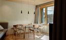 A modern furnished room with a wooden table and chairs. Large windows bring in plenty of daylight into the room.