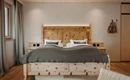 A modern bedroom with a wood bed and a cozy blanket. Soft colors and warm wood details create an inviting atmosphere.