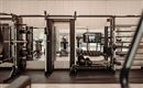 A modern gym with various machines and mirrors. The room is bright and well-equipped for an effective workout.