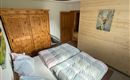 Ein gemütliches Schlafzimmer mit einem Doppelbett, bunten Bettdecken und einem Holzschrank. An der Wand hängt ein Kunstwerk eines Tieres.