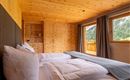 Ein gemütliches Schlafzimmer mit Holzverkleidung und großen Fenstern. Die Aussicht auf die Natur sorgt für eine entspannende Atmosphäre.