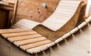 A detailed close-up of wooden loungers in a relaxing space. The ergonomic shapes convey a cozy atmosphere.