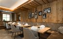 Ein gemütliches Restaurant mit Holzwänden und stilvollen Tischen. Die Wände sind mit Bildern geschmückt, und das Licht schafft eine einladende Atmosphäre.