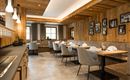Ein modernes Restaurant mit Holzverkleidung und eleganten Tischen. Die Atmosphäre ist einladend und gemütlich, mit sanfter Beleuchtung und dekorativen Bildern an den Wänden.
