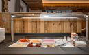 Ein Buffet mit frischem Obst und Joghurt in einer gemütlichen Umgebung. Die Holzverkleidung und die dekorativen Elemente verleihen dem Raum eine warme Atmosphäre.