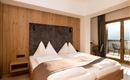Ein modernes Schlafzimmer mit einem großen Bett und Holzdekor. Der Raum verfügt über einen Balkon mit Aussicht.