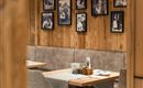 Ein gemütliches Restaurant mit Holzverkleidung und beigen Sitzen. An den Wänden hängen gerahmte Schwarz-Weiß-Fotos.