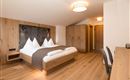 Ein modernes Schlafzimmer mit Holzverkleidung und einem großen Bett. Die gemütliche Atmosphäre wird durch weiche Beleuchtung und einen eleganten Schreibtisch ergänzt.