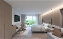 A modern hotel room with a large bed, a television, and a balcony. Bright wooden furniture and an elegant design create an inviting atmosphere.