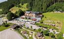 A modern hotel in a picturesque mountain landscape. Surrounded by green forests and a quiet parking lot.
