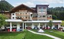 A modern hotel with an attractive outdoor area and balconies. Surrounded by a picturesque mountain landscape and green grass.