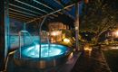 A relaxing hot tub under a covered area. Soft light and a peaceful garden environment create a cozy atmosphere.