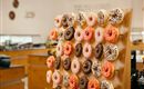 A wooden shelf with a colorful selection of donuts in various flavors and toppings. The donuts are neatly arranged and invite snacking.