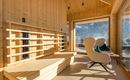 Ein modernes, helles Innenraum mit Holzverkleidung. Gemütliche Sitzgelegenheiten und große Fenster bieten einen Blick auf die Natur.