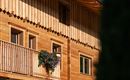 Ein Holzhaus mit einem Balkon, auf dem Blumen stehen. Die warmen Holzfarben verleihen dem Gebäude eine gemütliche Atmosphäre.