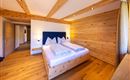 A modern bedroom with wooden paneling and a large double bed. The atmosphere is cozy and inviting.