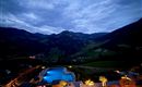 A beautiful view of the mountains at dusk. The illuminated pool in the center complements the idyllic scenery.