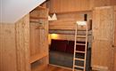 A cozy room with wood paneling. There is a loft bed, a small couch, and a wardrobe.