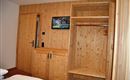 A cozy room with wood paneling and a TV. There is a wardrobe and a table.