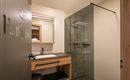 A modern bathroom with a glass shower and a wooden washbasin. The design is bright and inviting.