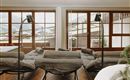 Ein modernes Wohnzimmer mit gemütlichen Liegen und großen Fenstern. Der Blick auf die Berge und das natürliche Licht sorgen für eine einladende Atmosphäre.