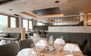 Ein modernes Restaurant mit stilvoll gedeckten Tischen. Große Fenster sorgen für viel Tageslicht und eine gemütliche Atmosphäre.