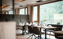 Ein elegantes Restaurant mit modernen Tischen und Stühlen. Große Fenster bieten eine Aussicht auf die grüne Landschaft.