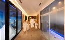 A woman with several children in bathrobes walks through a modern wellness area. The atmosphere is relaxed and inviting.