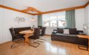A cozy living space with modern furniture. There is a dining table with chairs and a comfortable sofa.