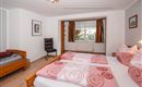 A cozy bedroom with two beds and colorful bedspreads. The windows let in light and the room has a friendly atmosphere.