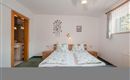 A stylish bedroom with a double bed and decorative cushions. The room has a bright, friendly atmosphere with easy access to the bathroom.