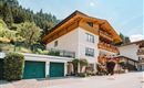 A charming house in alpine style with wooden balconies.  
Surrounded by green trees and a quiet street.