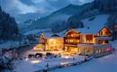 Ein gemütliches Hotel in einer verschneiten Landschaft. Die Lichter des Hotels strahlen in der Dämmerung und schaffen eine einladende Atmosphäre.