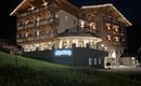 Ein modernes Hotelgebäude in malerischer Umgebung, beleuchtet von warmem Licht. Die Fassade ist einladend und freundlich gestaltet.