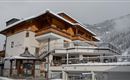 A charming hotel in the mountains, surrounded by snow-covered hills. The architecture combines traditional wooden design with modern elements.
