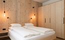 Ein modernes Schlafzimmer mit einem Doppelbett und Holzverkleidung. Die Wände sind aus hellem Holz, und es gibt stilvolle Wandlampen.