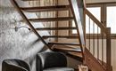 A modern hallway with a wooden staircase and cozy armchairs. A small table with a plant completes the cozy atmosphere.